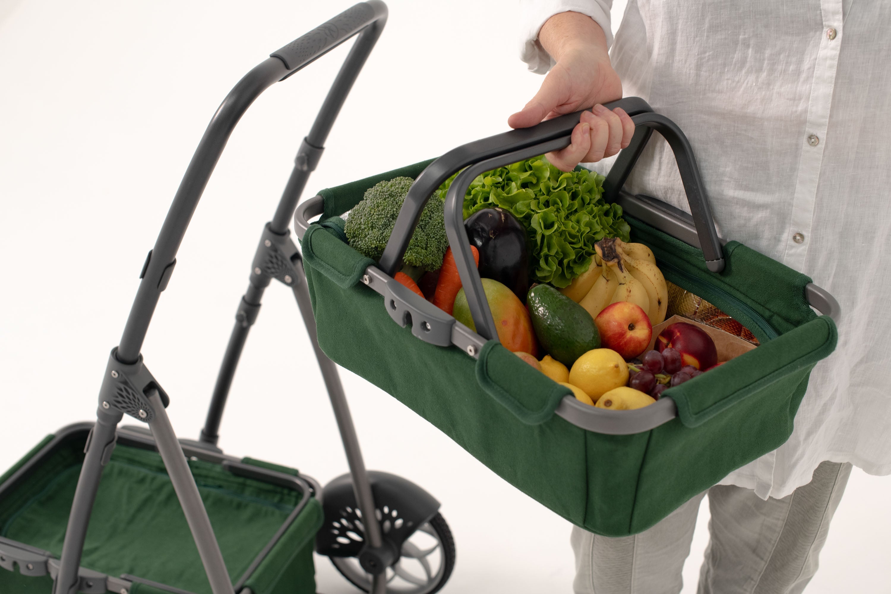 Image of a woman in a white shirt holding a green marketday basket filled with fruit and vegetables